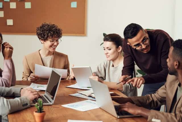 Employees working together with their laptops in front of them